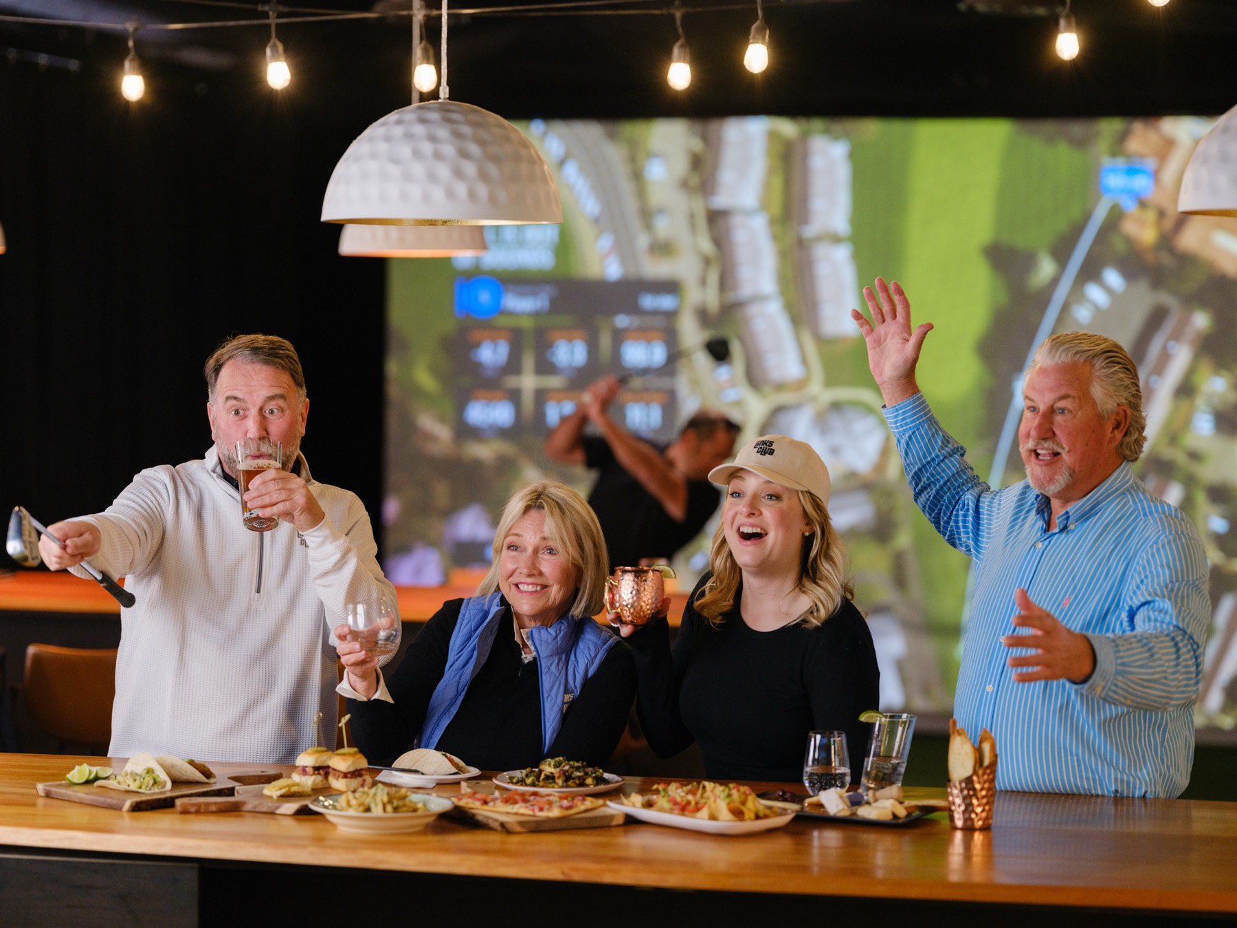 A group of friends celebrating with drinks and food at the Links Club bar