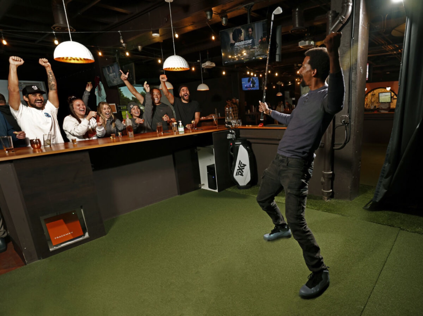 A golfer celebrating a shot while friends cheer at the Links Club bar
